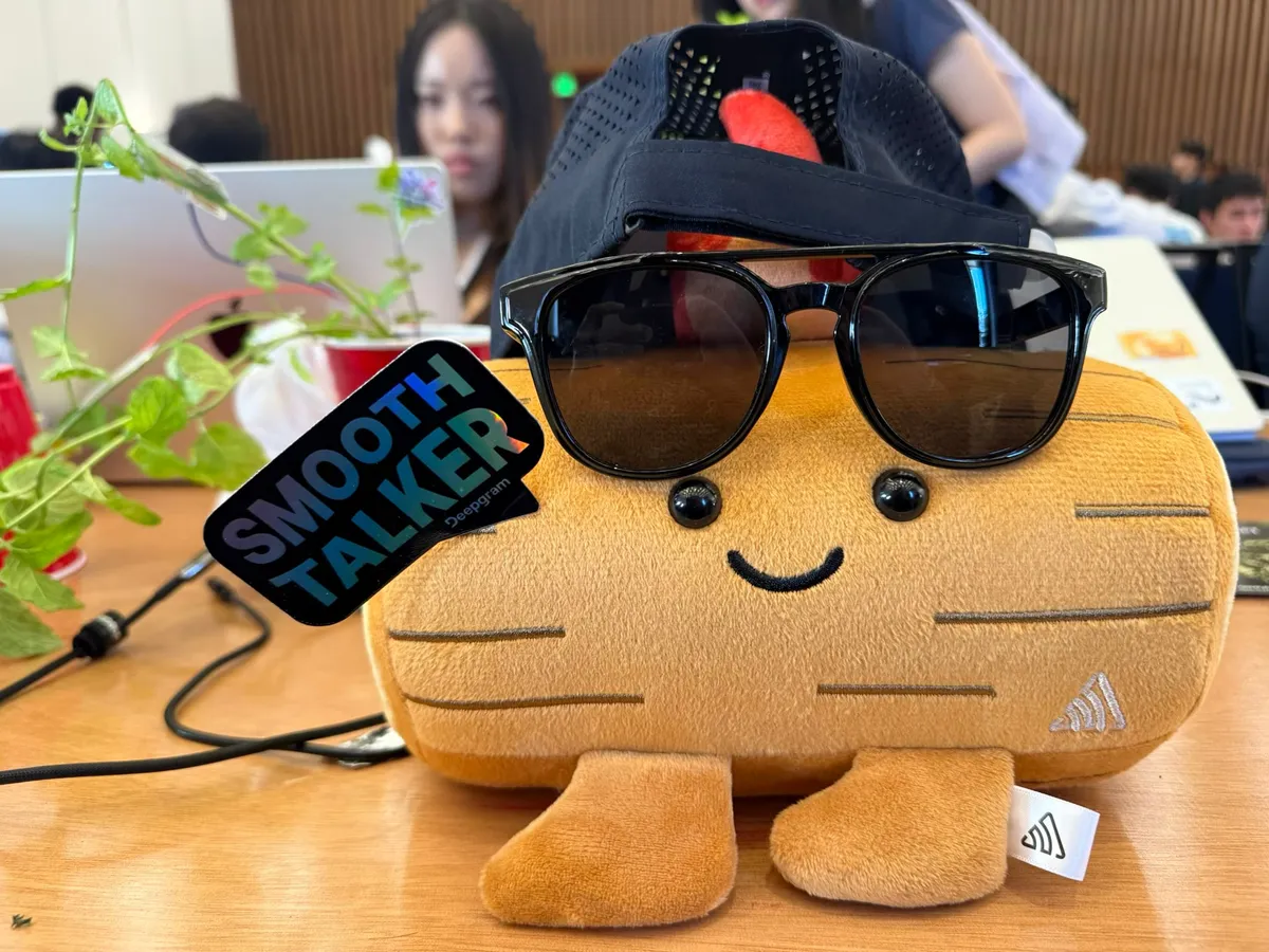 A plush toy wearing sunglasses with a Smooth Talker sticker at the hackathon